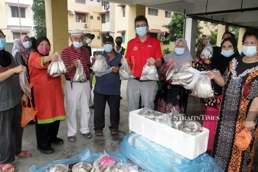 Dr Ko (fourth from right) with packages containing fish he distributed to some of the 30 recipients who are seen alongside him.  NSTP/VINCENT D’SILVA