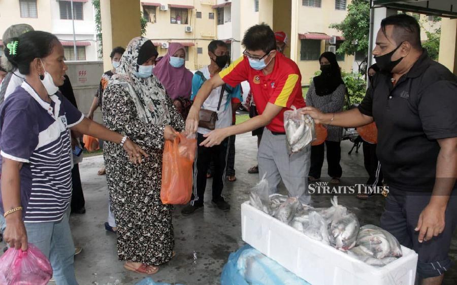 Dr Ko (second from right) places fish into packages meant for poor residents of Sri Stulang flats for their break of fast meals. NSTP/VINCENT D’SILVA
