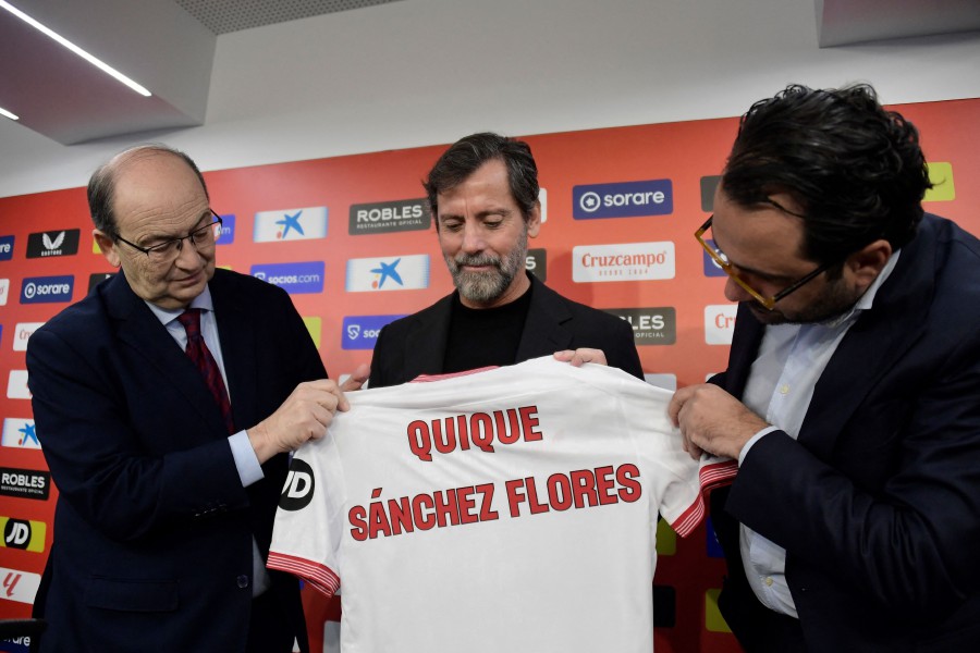 Sevilla FC's Spanish new coach Quique Sanchez Flores (C) poses for pictures holding a jersey with Sevilla's Spanish sports director Victor Orta (R) and Sevilla's president Jose Castro during his official presentation at the Ramon Sanchez Pizjuam stadium in Seville.- AFP PIC