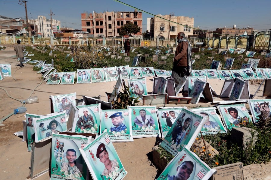 Yemenis pass portraits of late Yemenis, who were allegedly killed in the country’s ongoing war, before being placed on their graves at a cemetery during preparations for the anniversary of Martyr Day in Sanaa, Yemen. - EPA pic