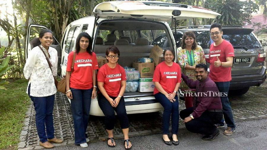 Cheah (far right, standing, in red) during a food distribution initiative by Kechara Soup Kitchen last year. NSTP/File pic