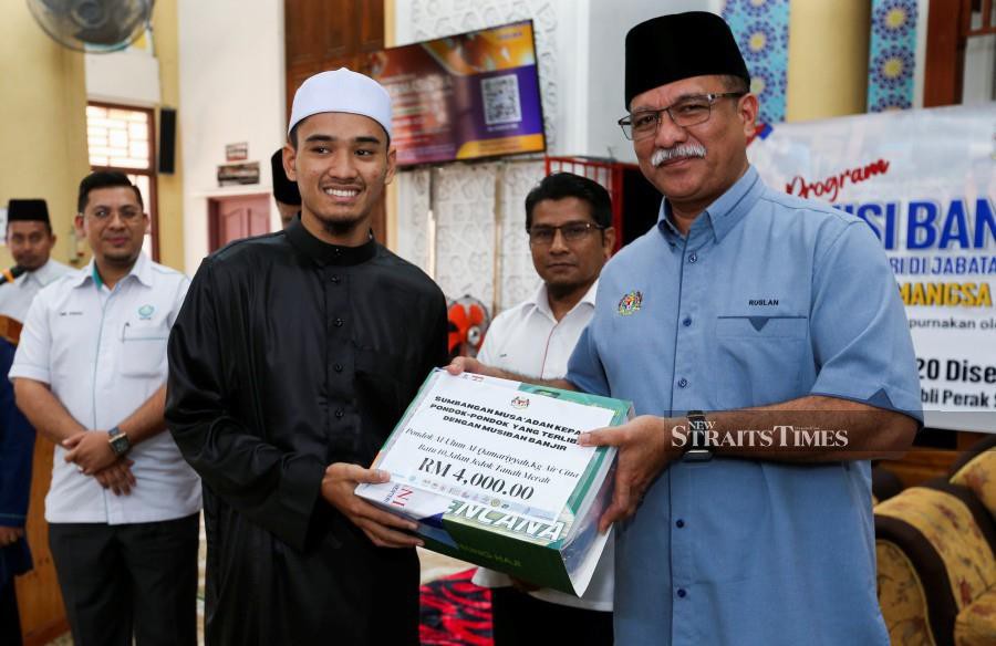 Jakim deputy director-general (operation) Ruslan Said (right) handing over the aid to during the ceremony at Masjid Jubli Perak Sultan Ismail Petra, Rantau Panjang.-NSTP/NIK ABDULLAH NIK OMAR