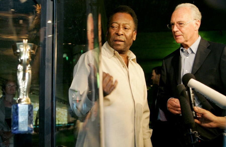 Football legend Pele of Brazil and former German player Franz Beckenbauer stand beside a replica of the first World Cup trophy 'Coupe Jule Rimet' during their visit to the exhibition 'Pelestation' in Berlin, Germany June 29, 2006. -REUTERS PIC