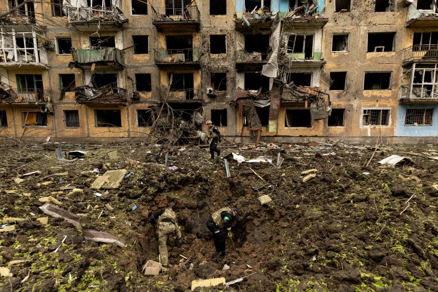 Ukrainian military personnel inspect the site of a missile strike in front of a damaged residential building, amid Russia's invasion, in Dobropillia, in the Donetsk region, Ukraine, April 30, 2022. - REUTERS PIC