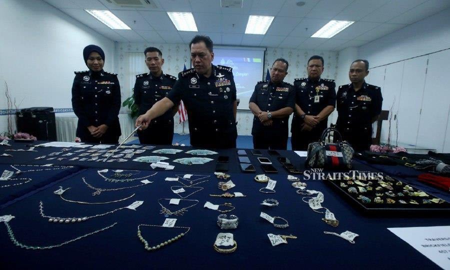 City police chief Datuk Rusdi Mohd Isa (centre) pointing at some of the items seized from the gang, during a press conference at Brickfields police station. -NSTP/HAIRUL ANUAR RAHIM