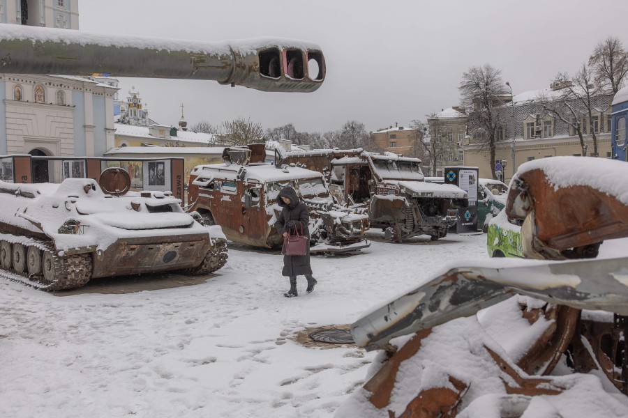 A woman walks past destroyed Russian military vehicles blanketed in snow, in front of Saint Michael's Golden-Domed Monastery, in downtown Kyiv. - AFP PIC