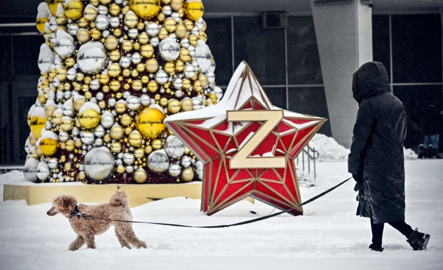 A woman walks her pet past a New Year decoration Kremlin Star, bearing a Z letter, a tactical insignia of Russian troops in Ukraine, in western Moscow. - APF PIC