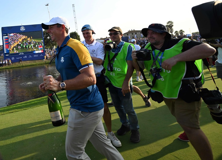 Europe's Northern Irish golfer, Rory McIlroy (L) walks with champagne as he celebrates ahead of the presentation ceremony following the final day of play in the 44th Ryder Cup at the Marco Simone Golf and Country Club in Rome. - AFP PIC