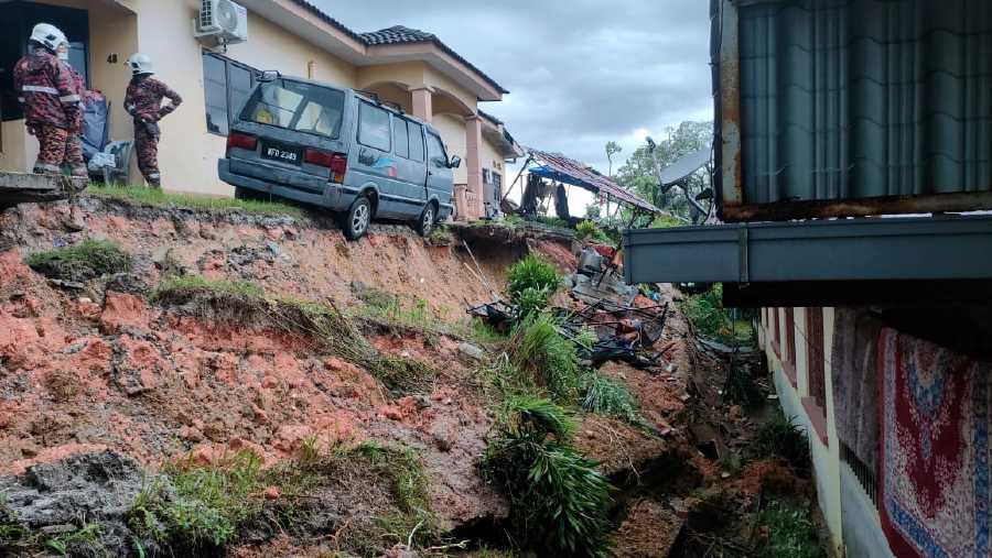 Firemen at the scene following the landslip in Kampung Dato Ahmad Said Tambahan Baru 1 in Manjoi. - Pic courtesy of Fire and Rescue Dept.