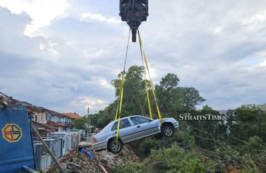 A crane is used to remove one of the vehicles which had fallen into the crater following the landslide in Taman Wawasan, Puchong. - Pic courtesy of police 