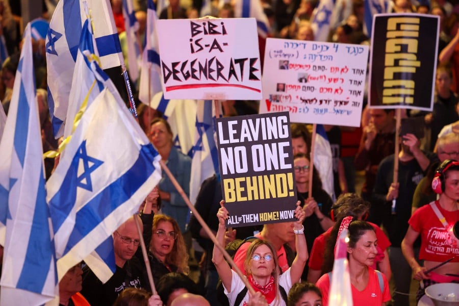 Israelis wave national flags and hold placards during an anti-government demonstration in the coastal city of Tel Aviv. - AFP PIC