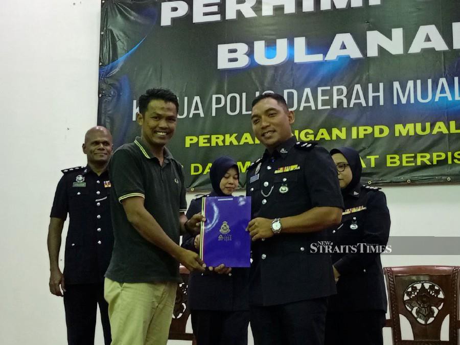Muallim district police chief Superintendent Mohd Hasni Mohd Nasir (right) presenting a certificate to Abdullah Abdul Talib during the ceremony in Tanjung Malim. -NSTP/MUHAMAD LOKMAN KHAIRI.