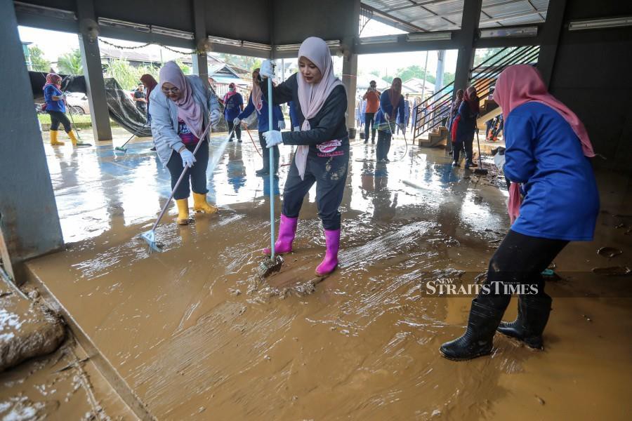 Umno Puteri chief Datuk Nurul Amal Mohd Fauzi (centre) helping out with the cleaning process in Ajil. -NSTP/GHAZALI KORI