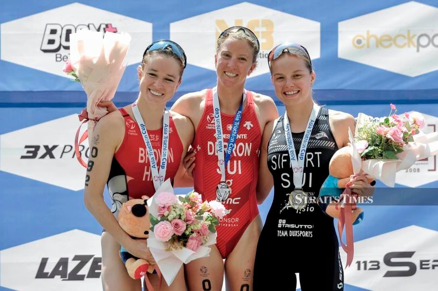 Julie Derron (centre) with Baiee Brown (left) and Alanis Siffert after the prize giving ceremony of the Asia Triathlon Cup Putrajaya at the Putrajaya Watersports Complex. - NSTP/AIZUDDIN SAAD