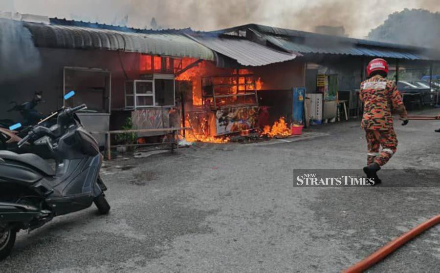 A fireman is seen inspecting the fire at the stalls in Batu Lanchang. - Pic courtesy of Fire and Rescue Dept