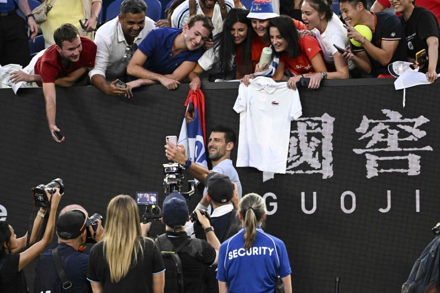 Serbia's Novak Djokovic poses for selfies with fans after his victory against USA's Taylor Fritz in their men's singles quarter-final match on day 10 of the Australian Open tennis tournament in Melbourne. - AFP PIC