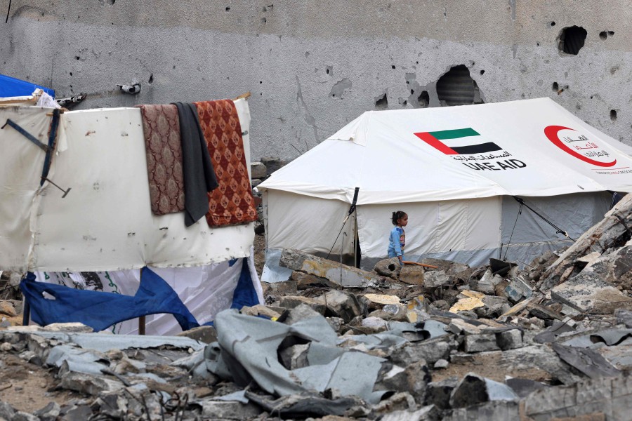 A Palestinian child walks amidst rubble in front of a tent bearing the logo of the Emirati Red Crescent and the mention of the UAE aid, at a makeshift camp housing displaced Palestinians in Rafah in the southern Gaza Strip. - AFP PIC