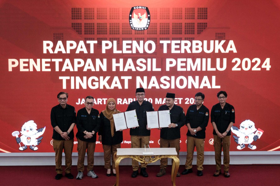 Indonesia's General Elections Commission (KPU) Chairman Hasyim Asy'ari (C) poses with commissioners with signed documents during the official tally announcement of the results of the February 2024 elections at the KPU office in Jakarta. - AFP PIC