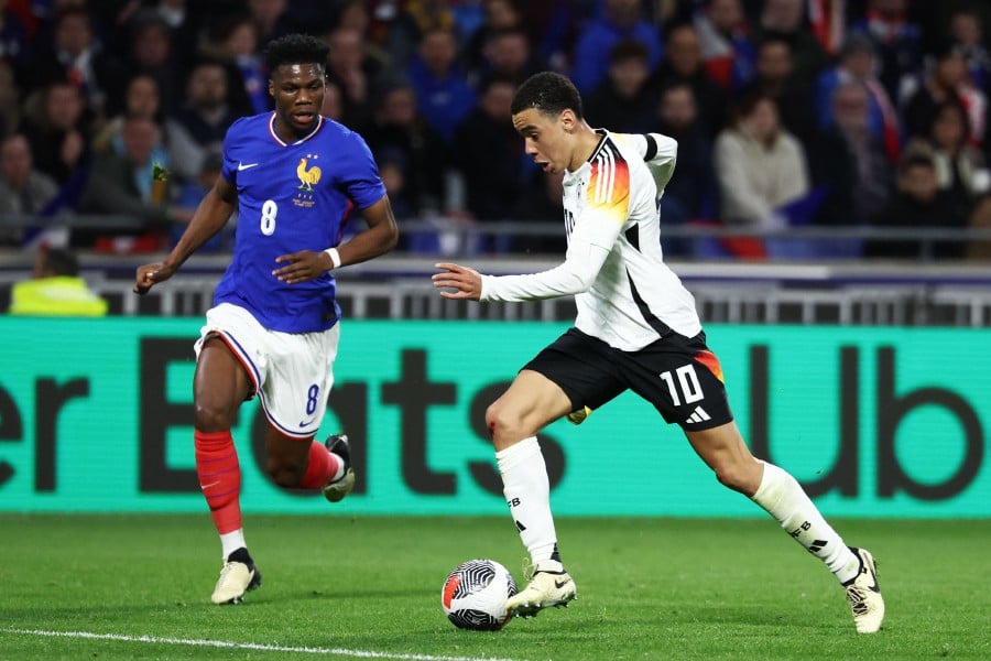 Germany's Jamal Musiala (R) runs with the ball ahead of France's Aurelien Tchouameni during the friendly match at the Groupama Stadium in Decines-Charpieu, near Lyon. - AF PPIC