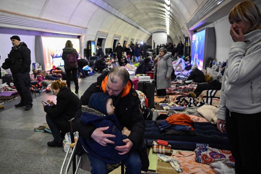 Sergyi Badylevych (C), 41, kisses his baby, as his wife Natalia Badylevych (R), 42, looks on in an underground metro station used as bomb shelter in Kyiv. - AFP PIC