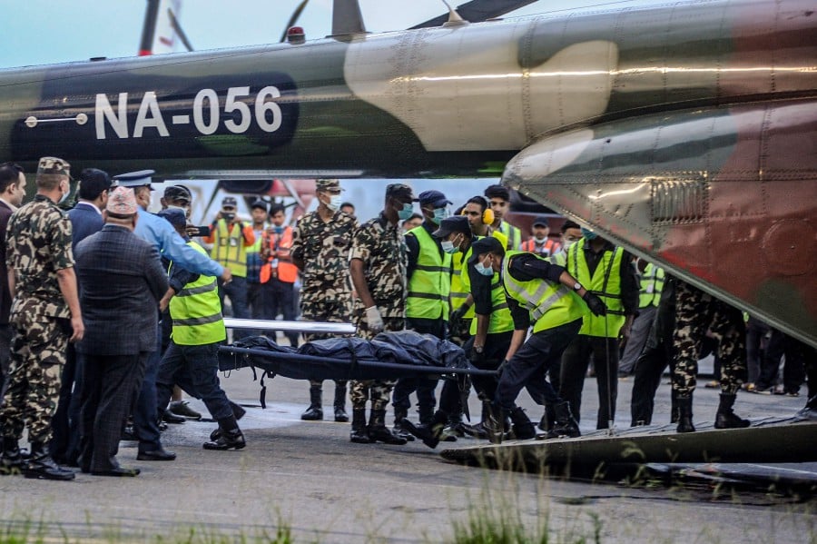 Nepal’s security personnel carry the bodies of victims of a crash of a Twin Otter aircraft operated by Tara Air that crashed earlier in the Himalayas with 22 people on board, brought to Kathmandu on an army helicopter at Tribhuvan International Airport in Kathmandu. - AFP PIC