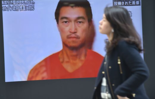 A pedestrian walks past a TV screen in Tokyo showing news reports about Japanese journalist Kenji Goto being held by Islamic militants. The Islamic State group has said it executed one of two Japanese hostages it has been holding, in an apparent beheading that has been slammed by leaders around the world. AFP PHOTO