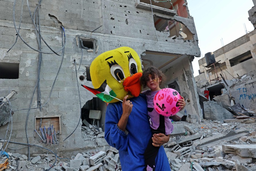 - A Palestinian clown carries a child during a show amidst the rubble of a building destroyed in the latest round of fighting between Israel and Palestinian militants, in Rafah in the southern Gaza Strip. - AFP PIC