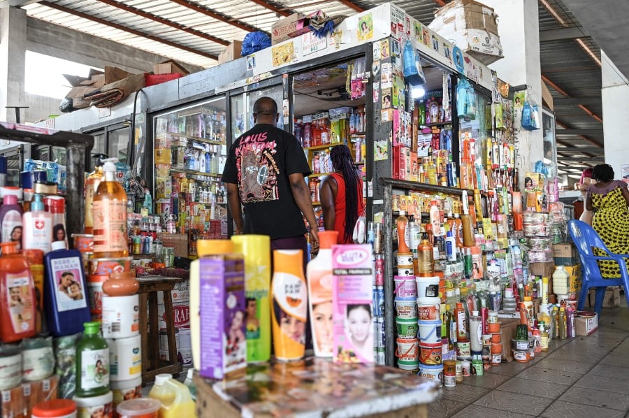 Customers approach a shop selling skin lightening cosmetic products at the Koumassi market, in Abidjan. - AFP PIC