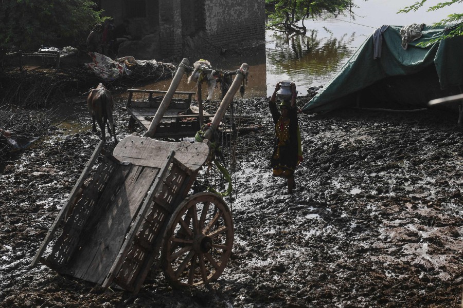 A flood affected woman carries a water pot across a muddy area after heavy monsoon rains in Jacobabad, Sindh province. - AFP PIC