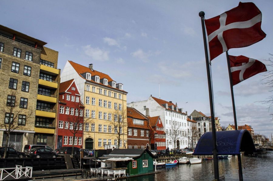 Danish flags fly from flagpoles opposite residential homes and apartments in the Christianshavn district of central Copenhagen, Denmark, on Thursday, March 28, 2013. Photographer: Freya Ingrid Morales/Bloomberg