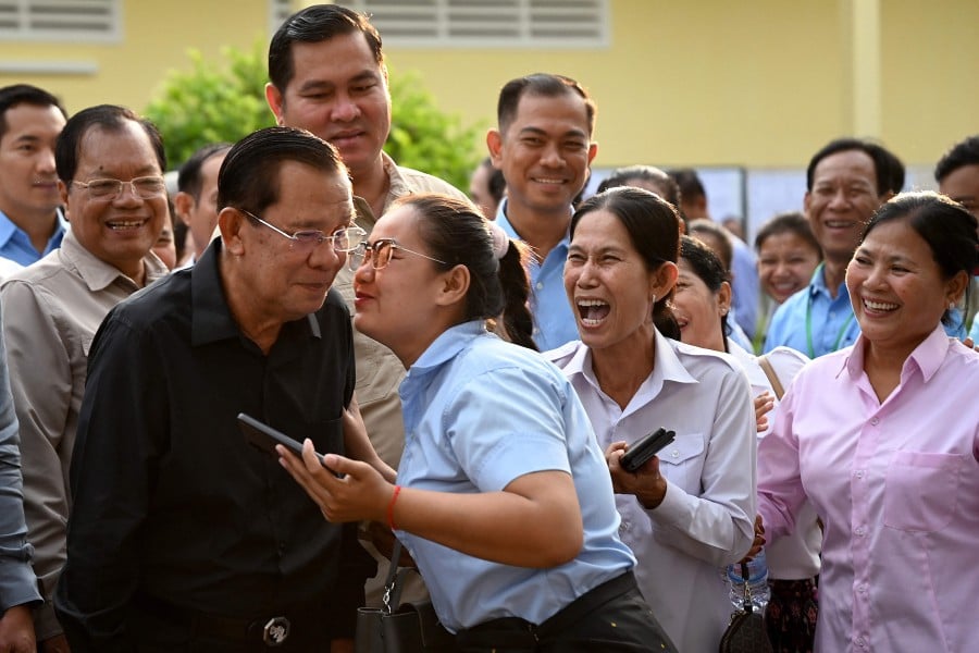 Member of parliament and Cambodia's former prime minister Hun Sen (front L) receives a kiss from a commune councillor (C) after he cast his vote at a polling station during the Senate election in Takhmao city, Kandal province. - AFP PIC