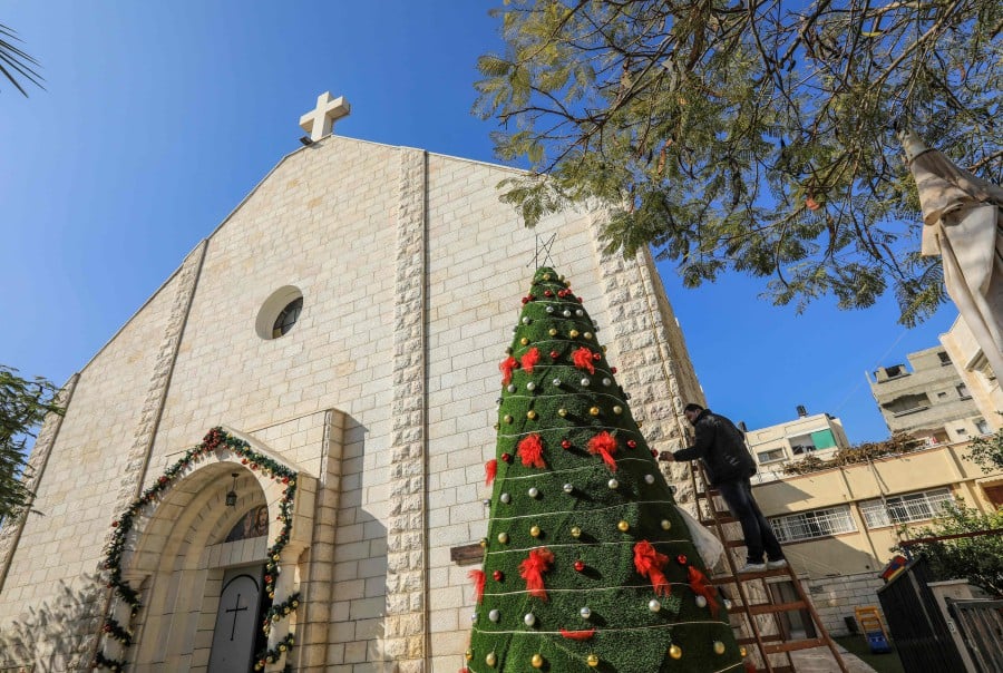  A man decorates a christmas tree outside the Roman Catholic Church of the Holy Family in Gaza City. - AFP FILE PIC