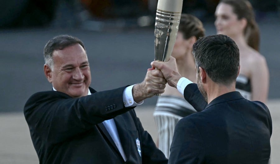 President of the Hellenic Olympic Committee and IOC member Spyros Capralos (L) hands the Olympic torch to President of the Paris 2024 Olympics and Paralympics Organising Committee (Cojo) Tony Estanguet (C) during the handover ceremony of the Olympic Flame for the Paris 2024 Summer Olympic and Paralympic Games at Panathinean stadium in Athens. - AFP PIC 