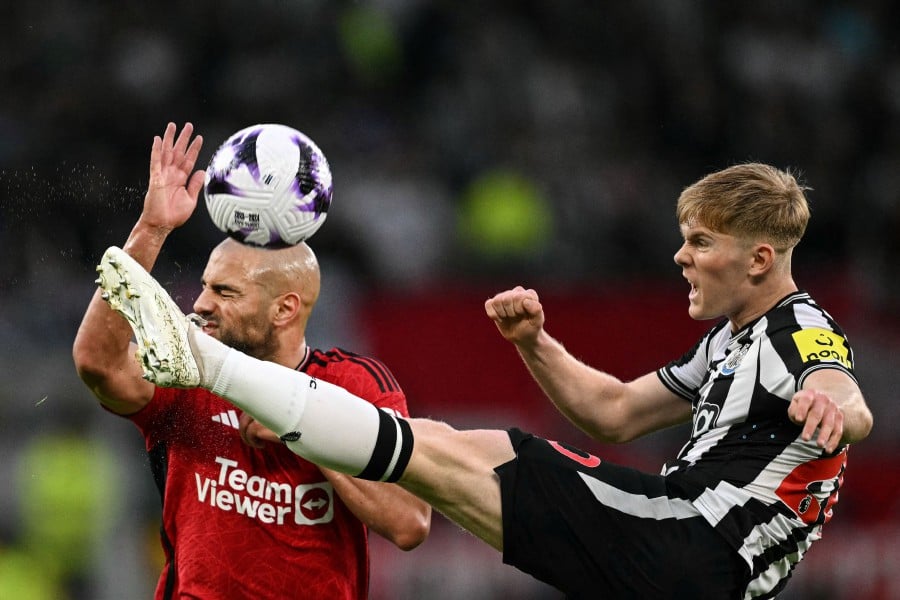  Newcastle United's Lewis Hall (R) shoots the ball past Manchester United's Sofyan Amrabat during the English Premier League match at Old Trafford in Manchester. - AFP PIC