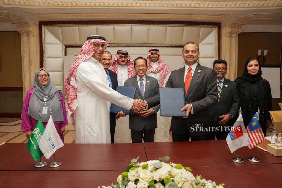 Saudi Exim chief executive officer Saad Al-Khalb exchanging the MoU documents signed with Exim Bank Malaysia president and chief executive offer Arshad Ismail. The signing was witnessed by Deputy Finance Minister 1 Datuk Seri Ahmad Maslan (centre).