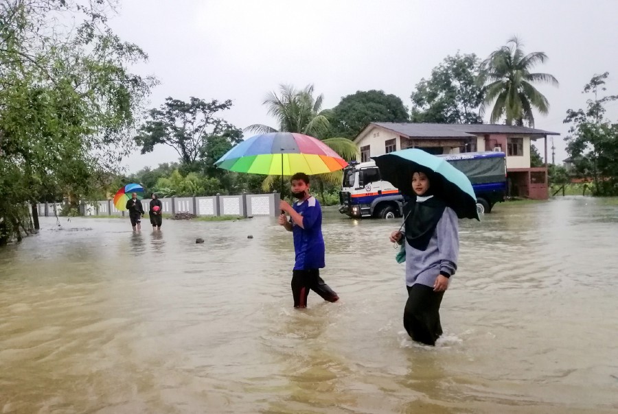 Locals brave the flood waters in Kampung Sri Kulim Melor in Kota Baru. - BERNAMA pic