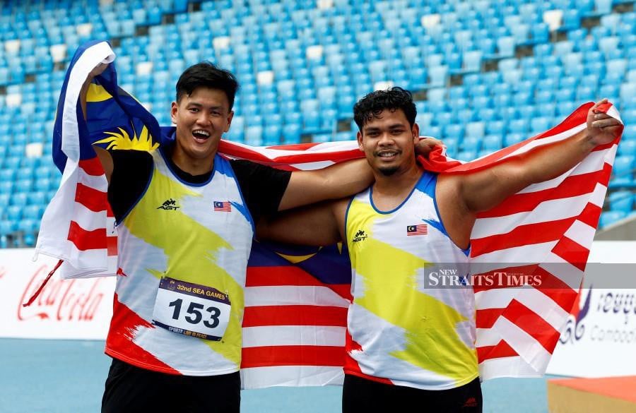 Malaysia's Jackie Wong Siew Cheer celebrates winning silver alongside bronze winner Malaysia's Sadat Marzuqi Ajisan in the men's hammer throw final. - AFP PIC