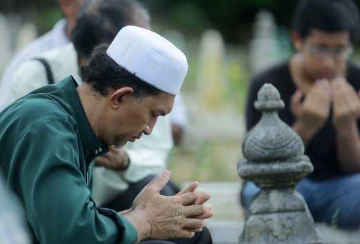 Wan Mazlan Wan Hassan prays for his daughter during the funeral Kampung Lemal Muslim cemetery. Pix by FATHIL ASRI.