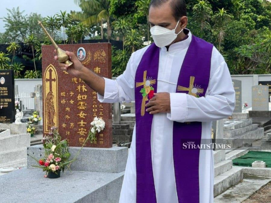 Church of the Immaculate Conception parish priest Reverend Father Jude Miranda blessing the graves for All Souls’ Day at the Kelawai Road cemetery this morning. - Pix by Marina Emmanuel 