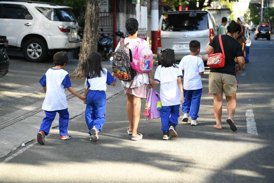 Parents accompany their children from school after their classes in Manila on April 5, 2024. Thousands of schools in the Philippines suspended in-person classes on April 5, the education department said, as parts of the tropical country endured dangerously high temperatures. -- AFP
