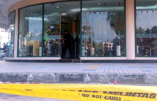 A man hurled what appeared to be a bomb at a row of ATM machines in a bank at Bukit Jambul earlier this morning. Pix by Shahnaz Fazlie Shahrizal