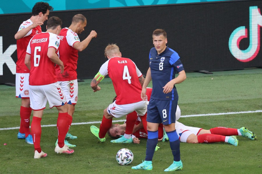  Players gather as Denmark's midfielder Christian Eriksen (bottom) lies on the pitch during the UEFA EURO 2020 Group B football match between Denmark and Finland at the Parken Stadium in Copenhagen. - AFP Pic