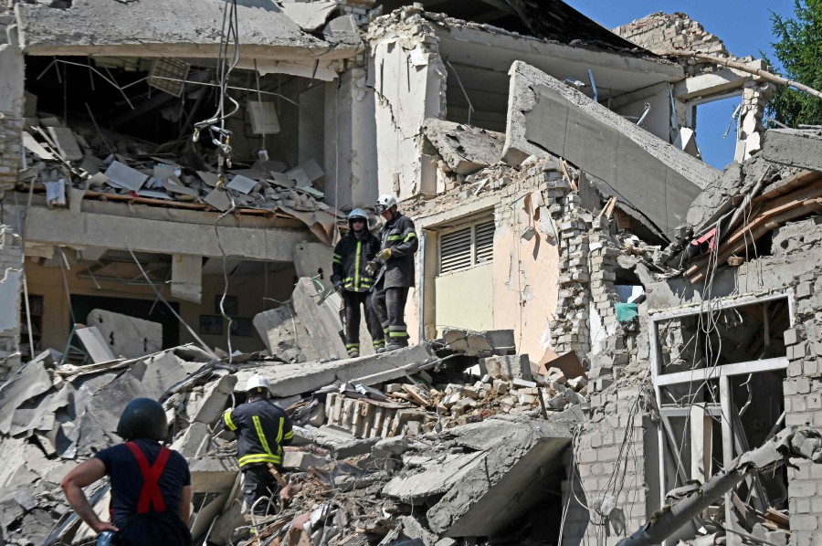 Rescuers work in the wreckages of a destroyed school after being hit by a rocket in Kharkiv. - AFP PIC