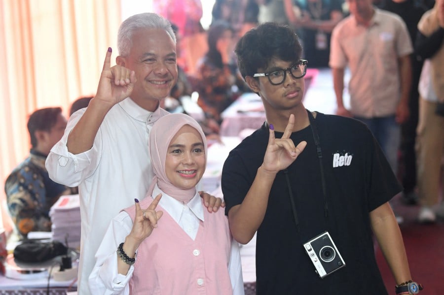 Presidential candidate Ganjar Pranowo, his wife Siti Atikoh and son Alam Ganjar show their inked fingers at a polling station in Semarang, Central Java, Indonesia. - REUTERS PIC