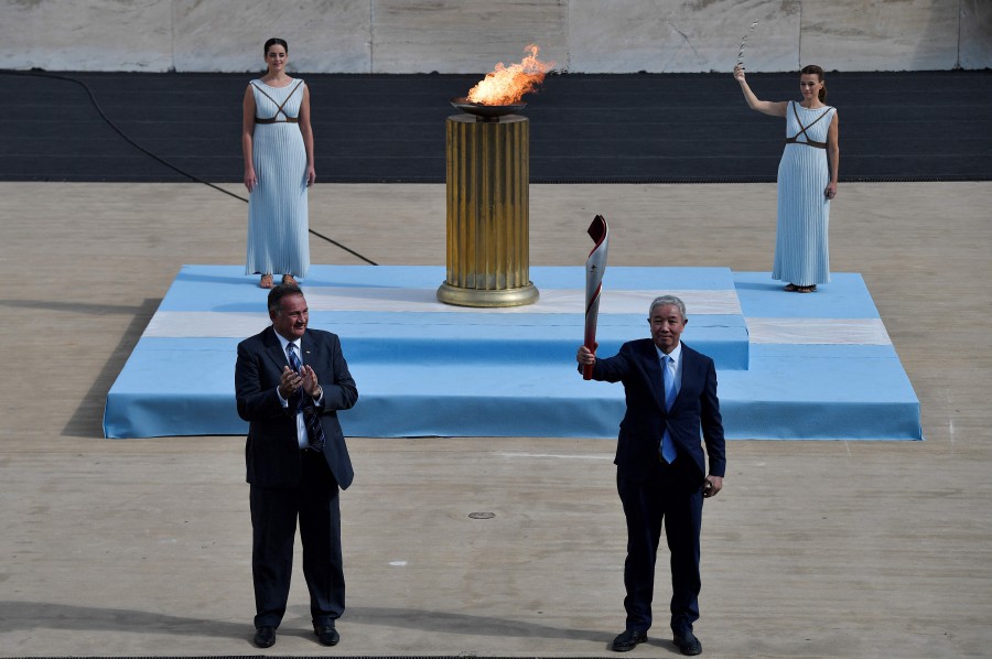 IOC vice-president Yu Zaiqing (R) holds the torch with the Olympic Flame, next to President of the Hellenic Olympic Committee and IOC member Spyros Capralos (L), during the handover ceremony of the Olympic Flame for the Beijing 2022 Winter Olympics at the Ancient Olympia archeological site, birthplace of the ancient Olympics in southern Greece. - AFP PIC