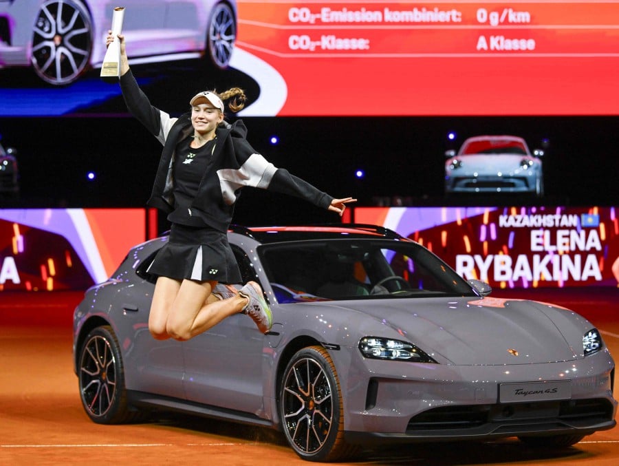 Kazakhstan's Elena Rybakina holds her trophy as she jumps inf front of her prize, a Porsche Taycan 4S Sport Turismo car, during the victory ceremony after she defeated Ukraine’s Marta Kostyuk in the final match at the Women's Tennis Grand Prix WTA tournament in Stuttgart, southwestern Germany. - AFP PIC