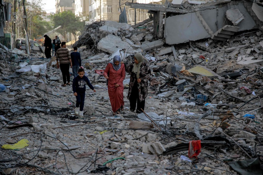 Palestinians walk amidst the rubble of destroyed buildings in Gaza City on November 26, 2023, on the third day of a truce between Israel and Hamas. -AFP PIC