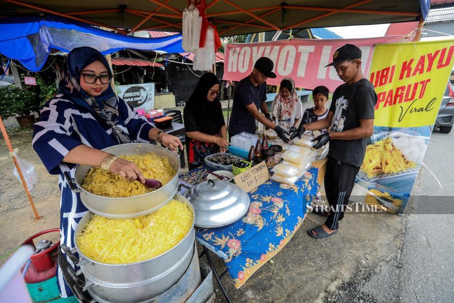 Sulizawati Sulong, (left) preparing an order for her customer at her stall in Wakaf Mempelam, Kuala Terengganu. -NSTP/GHAZALI KORI