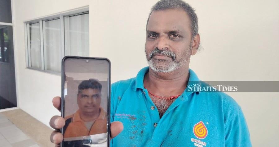M. Manivannan shows a picture of Jayakumar who perished in the fire. - NSTP/ZULIATY ZULKIFFLI