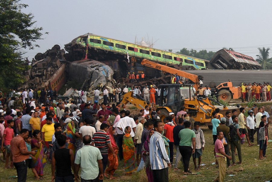 People stand next to damaged coaches after two passenger trains collided in Balasore district in the eastern state of Odisha, India. - REUTERS PIC 